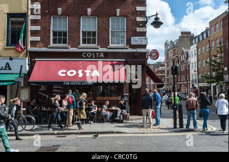 Soho Londra angolo di strada in scena con la Costa Coffee shop e le persone al di fuori in Old Compton Street in una giornata di sole Foto Stock