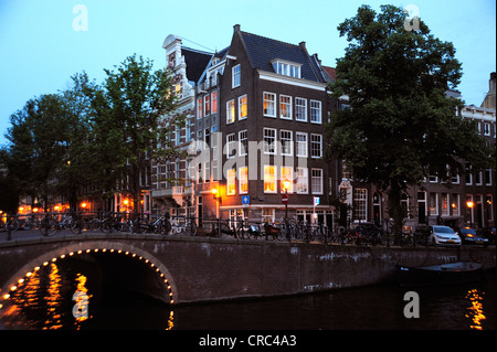 Ponte illuminato e case residenziali al crepuscolo, Prinsengracht, Leliegracht, la cittadina di canale nel centro storico della città, Foto Stock
