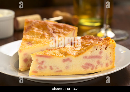 Due fette di formaggio e prosciutto quiche con vino bianco nel retro (messa a fuoco selettiva, Focus sulla superficie frontale del primo strato) Foto Stock