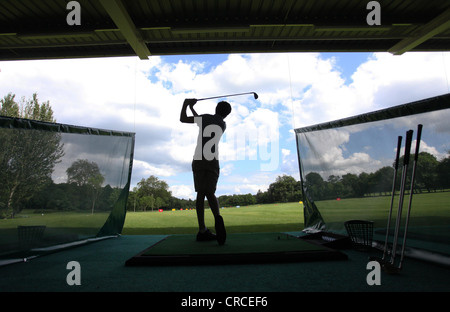 Un golfista praticando nella gamma di guida.. Foto Stock