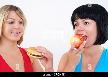 Due donne mangiare hamburger e Apple Foto Stock