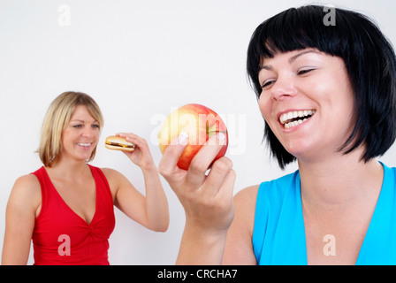 Due donne mangiare hamburger e Apple Foto Stock