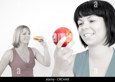 Due donne mangiare hamburger e Apple Foto Stock
