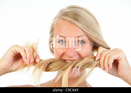 Giovane donna bionda mordere nei suoi capelli Foto Stock