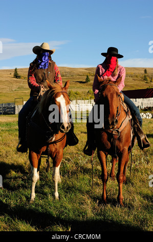 Cowgirls con fazzoletti da naso e da taschino oltre le loro facce seduta su cavalli, Saskatchewan, Canada, America del Nord Foto Stock