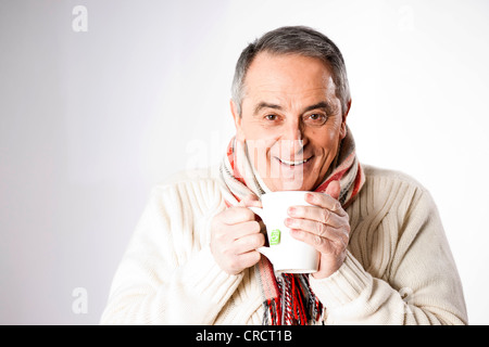 Felice l'uomo senior in abbigliamento invernale bicchiere di tè Foto Stock