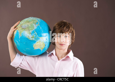 Ragazzo adolescente holding globe Foto Stock