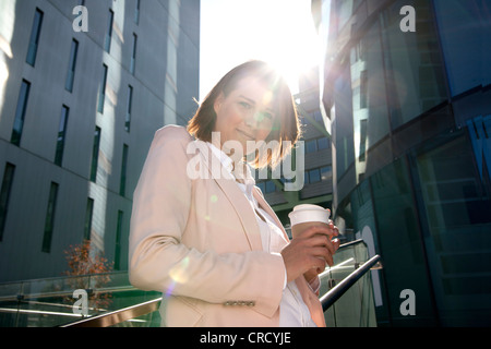 Imprenditrice sorridente con caffè per andare all'aperto Foto Stock