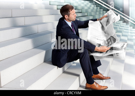 Imprenditore quotidiano di lettura su scale Foto Stock