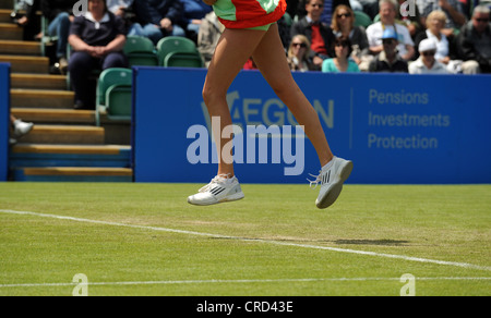 Chiusura del tennis femminile giocatori piedi saltando in aria mentre lei colpisce un servire Foto Stock