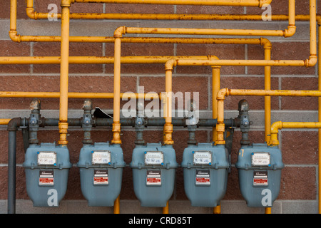 Cinque Enbridge contatori del gas. Una fila di contatori del gas collegati da un dedalo di tubazioni gialle la manutenzione di un edificio commerciale. Foto Stock