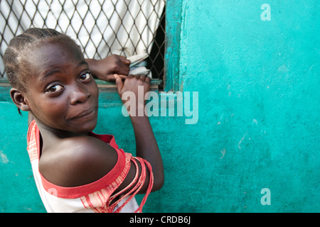 Una ragazza guarda indietro mentre si guarda il TV tramite una finestra nel West Point baraccopoli di Monrovia, Montserrado county, Liberia lunedì un Foto Stock