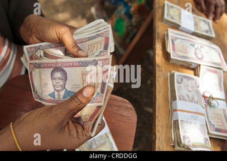 Un membro del personale di una banca locale conta soldi durante una cassa sociale programma di trasferimento di distribuzione Foto Stock