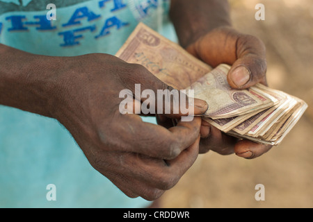 Un uomo conta i soldi che ha appena ricevuto da una cassa sociale programma di trasferimento nel villaggio di Julijuah, Contea Bomi, Liberia Foto Stock