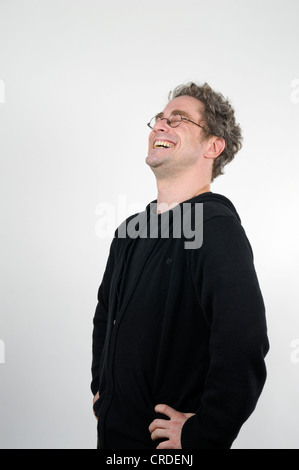 Giovane uomo con gli occhiali a ridere con tutto il cuore e con le mani sui fianchi Foto Stock