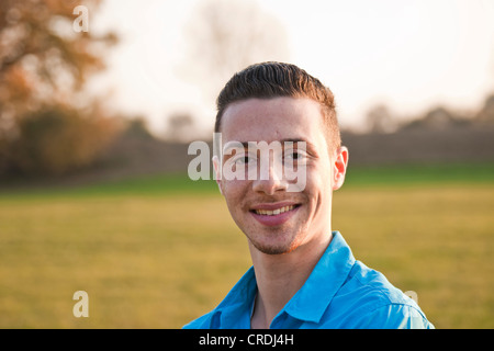 Sorridente giovane uomo, ritratto, su di un prato di autunno Foto Stock