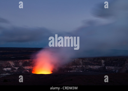 Il magma di Halema'uma'u cratere del Kilauea Caldera illuminando la salita del biossido di zolfo plume contro il cielo di sera Foto Stock