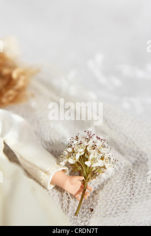 Una stretta di mano di una sposa la bambola tenendo un mazzo di fiori. Foto Stock