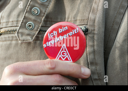 Mano tenendo il pulsante con il logo del sindacato IG Metall, "Ich bin streikbereit', Tedesco per 'Io sono pronto a colpire' Foto Stock