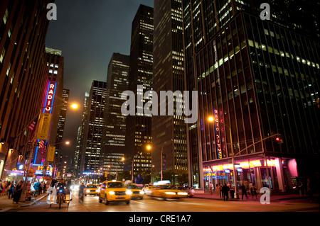 I grattacieli illuminati e traffico di notte, 6th Avenue angolo della 51st West, Midtown Manhattan, New York City, Stati Uniti d'America Foto Stock