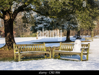 Pupazzo di neve seduta su una panchina in coperta di neve Kew Gardens in inverno, Royal Botanic Gardens, Londra Foto Stock