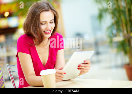 Ragazza sorridente di trascorrere del tempo in una street cafe con tavoletta digitale Foto Stock