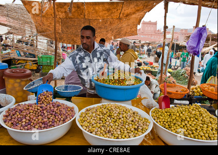 Pressione di stallo di mercato su un souk o bazaar, il giovane uomo che offrono diversi tipi di olive in grandi ciotole, Zagora, Valle di Draa, Marocco Foto Stock