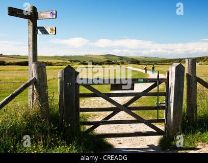 Segnaletica nelle Cuckmere Valley vicino a Cuckmere Haven con gate e due persone a piedi il percorso di chalk East Sussex, England, Regno Unito Foto Stock