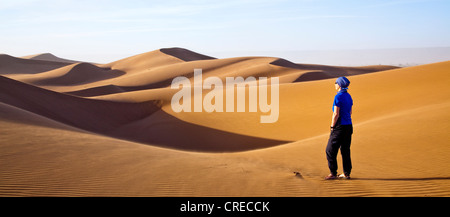 Donna che cammina nelle dune, Erg Chegaga regione, Sahara Deserto vicino a Mhamid, Marocco, Africa Foto Stock