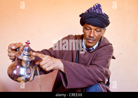 Berber indossando un Djellaba, un abito tradizionale, versando il tè alla menta, Alto Atlante vicino Asni, Marocco, Africa Foto Stock