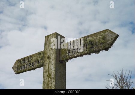 Un sentiero pubblico signpost ricoperte da licheni contro un blu e il cielo nuvoloso SOUTH WEST COAST PATH Devon England Foto Stock