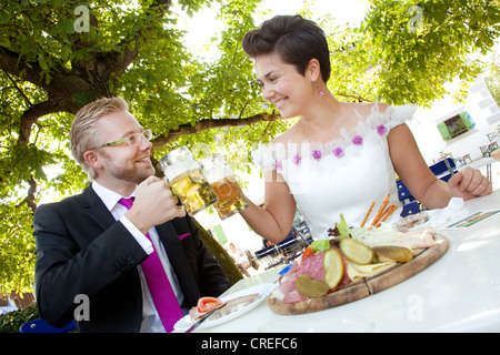 Coppia di sposi avente un pasto leggero e bere birra in una birra bavarese e giardino, Regensburg, Baviera, Germania, Europa Foto Stock