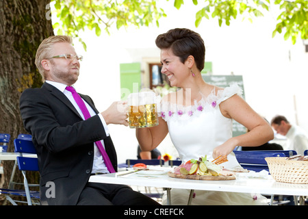 Coppia di sposi avente un pasto leggero e bere birra in una birra bavarese e giardino, Regensburg, Baviera, Germania, Europa Foto Stock