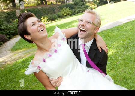 Sposo portando la sua sposa, in un parco a Regensburg, Baviera, Germania, Europa Foto Stock