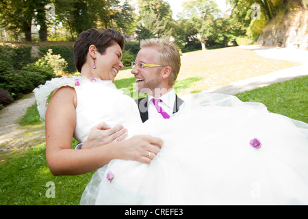 Sposo portando la sua sposa, in un parco a Regensburg, Baviera, Germania, Europa Foto Stock