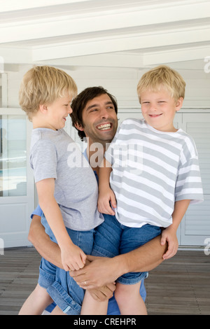 Padre sorridente holding figli Foto Stock