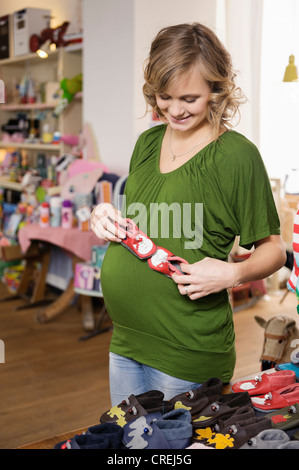 Donna incinta acquistare scarpe per bambini Foto Stock