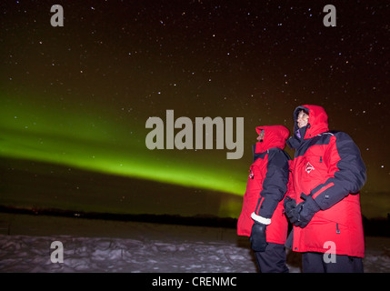 Giovane donna e uomo, guardando il verde polare settentrionale (luci di aurora boreale), vicino a Whitehorse, Yukon Territory, Canada Foto Stock