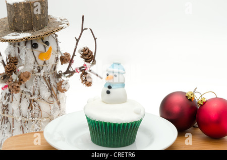 Tortina di Natale decorato con glassa bianca e un pupazzo di neve con decorazioni di Natale - studio shot con uno sfondo bianco Foto Stock
