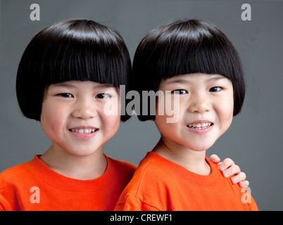 Allegra ragazza cinese gemelli cinque anni indossando orange T shirt Foto Stock
