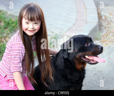 Sorridente bambina con un grande cane nero Foto Stock