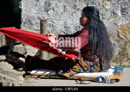 Una donna tribale utilizza un telaio dorsalino per rendere al panno rosso in GYASUMDO villaggio vicino Manang sul circuito di Annapurna, Nepal, Kathmandu Foto Stock