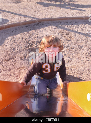 Little Boy salendo una fetta su un parco giochi Foto Stock