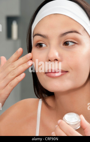 Donna di applicare una crema idratante in specchio Foto Stock