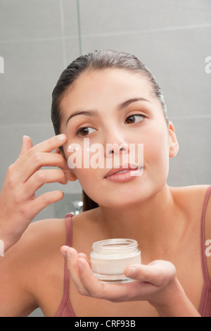 Donna di applicare una crema idratante viso a Foto Stock