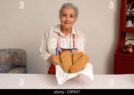 Donna anziana la produzione di pane in salotto Foto Stock