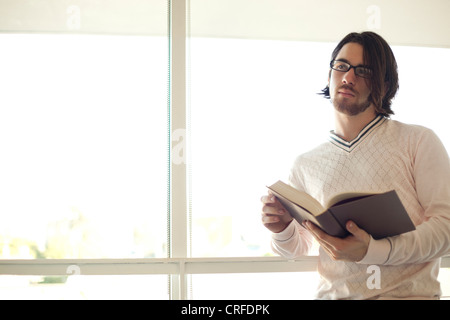 Considerato giovane uomo tiene un libro aperto Foto Stock