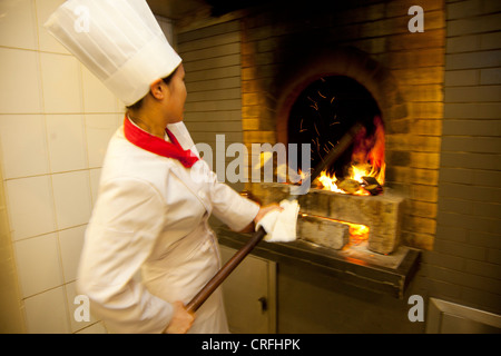 La sola femmina chef d'anatra di Pechino solleva anatre in e fuori dei forni. Quanjude Roast Duck Restaurant in Wangfujing di Pechino Foto Stock