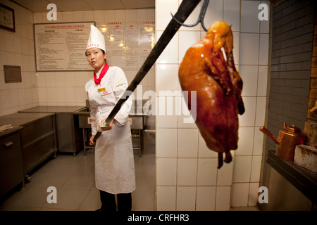 La sola femmina chef d'anatra di Pechino solleva anatre in e fuori dei forni. Quanjude Roast Duck Restaurant in Wangfujing di Pechino Foto Stock