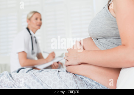 Medico a parlare con una donna in stato di gravidanza Foto Stock